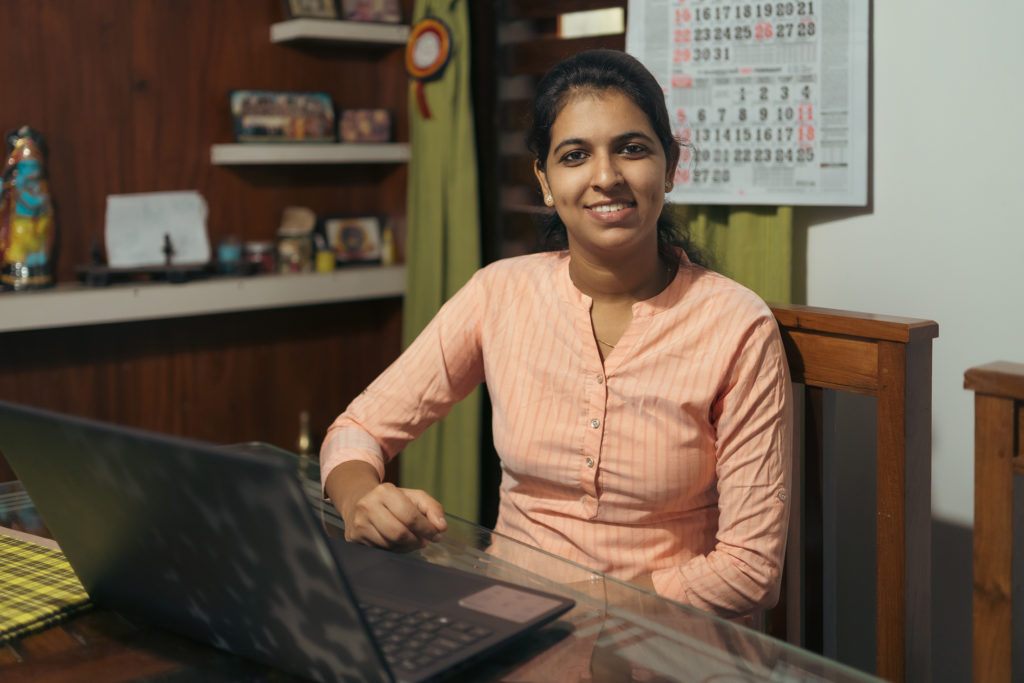 A woman sitting at a dining table working on her laptop