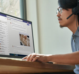 Young man wearing a headset while sitting at a desktop computer