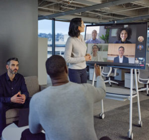 Three people in an open space of an office building in a Teams meeting with six people attending virtually