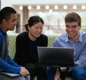Three people share a laptop computer