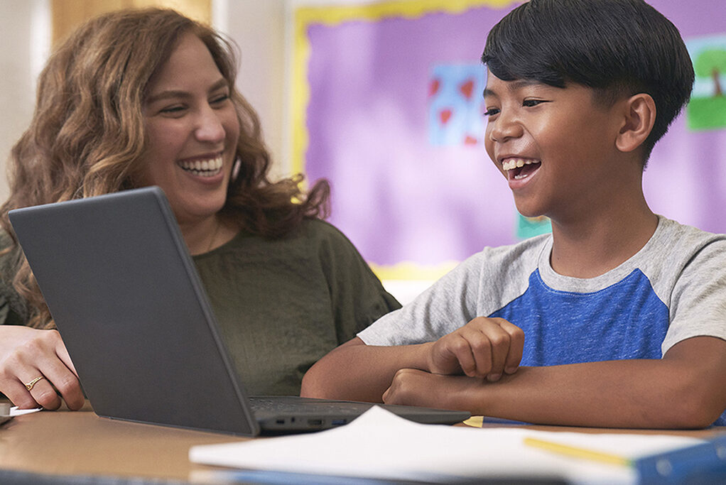 Teacher and student enjoy a laugh together in front of a laptop computer