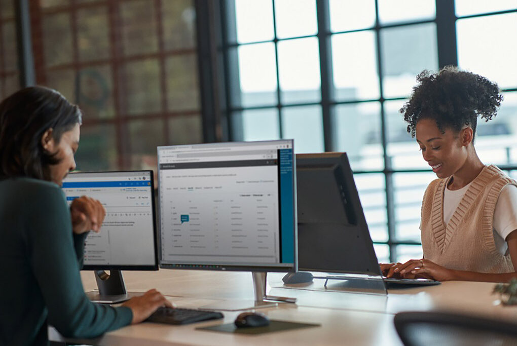 Two young adults working on desktop computers in an office