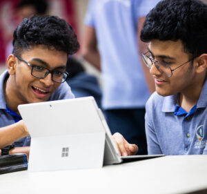 Two male students discuss what's on their lap[top computer