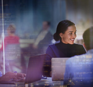 Stock photo showing people working in front of computer screens in an office setting.