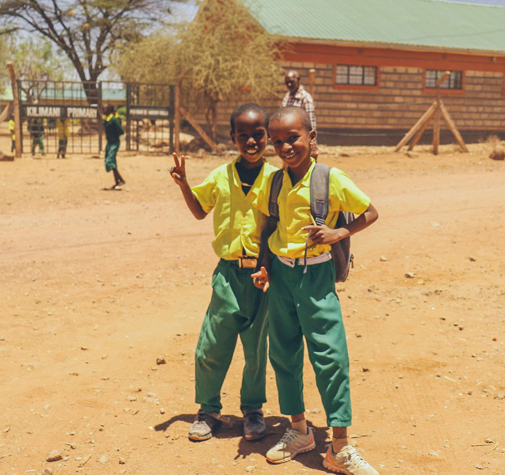 Two primary school kids in front of a school in Africa