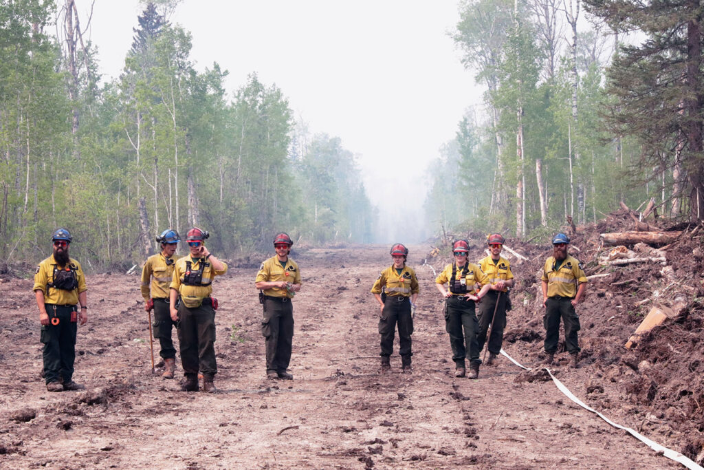 Firefighters stand in a fire guard