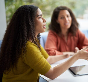 Woman talking at an office meeting while another woman looks on