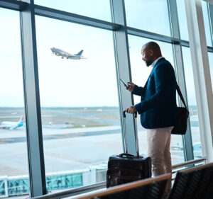 Man smiles as he interacts with someone on his phone while waiting for his flight at an airport