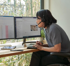 Man wearing headset while working on a computer with two displays