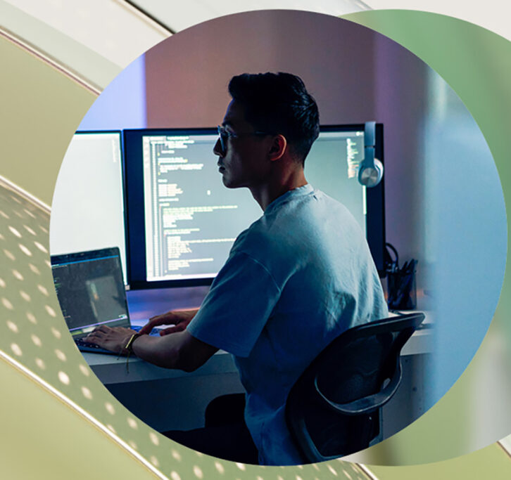 Man working at a desktop computer with dual monitors