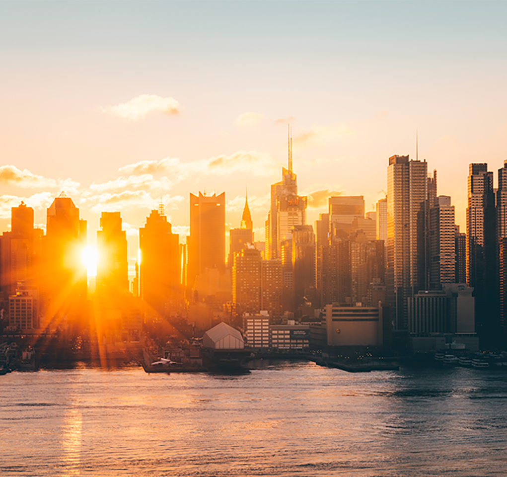 Sun rising or setting behind a view of city skyscrapers