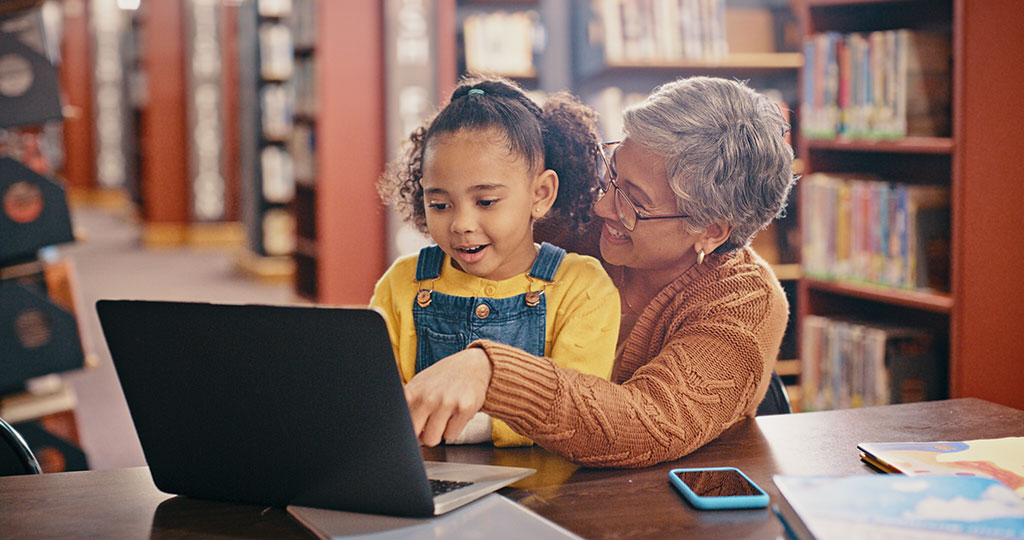 Older adult helping a child on a computer