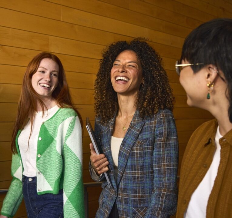 Three students sharing a laugh as they walk down a school hall