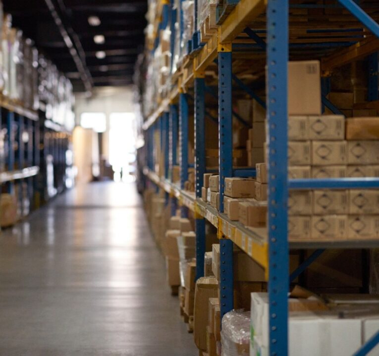 View down an aisle of a warehouse with boxes on shelves