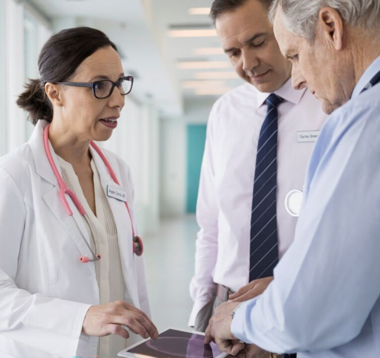 Three physicians conversing in a hallway.