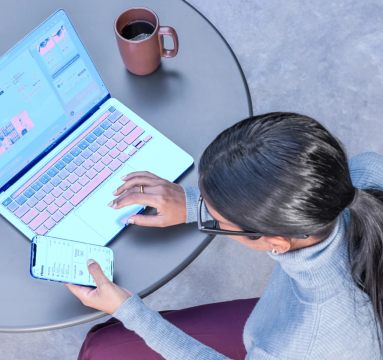 View from above of a woman working at her phone and laptop computer