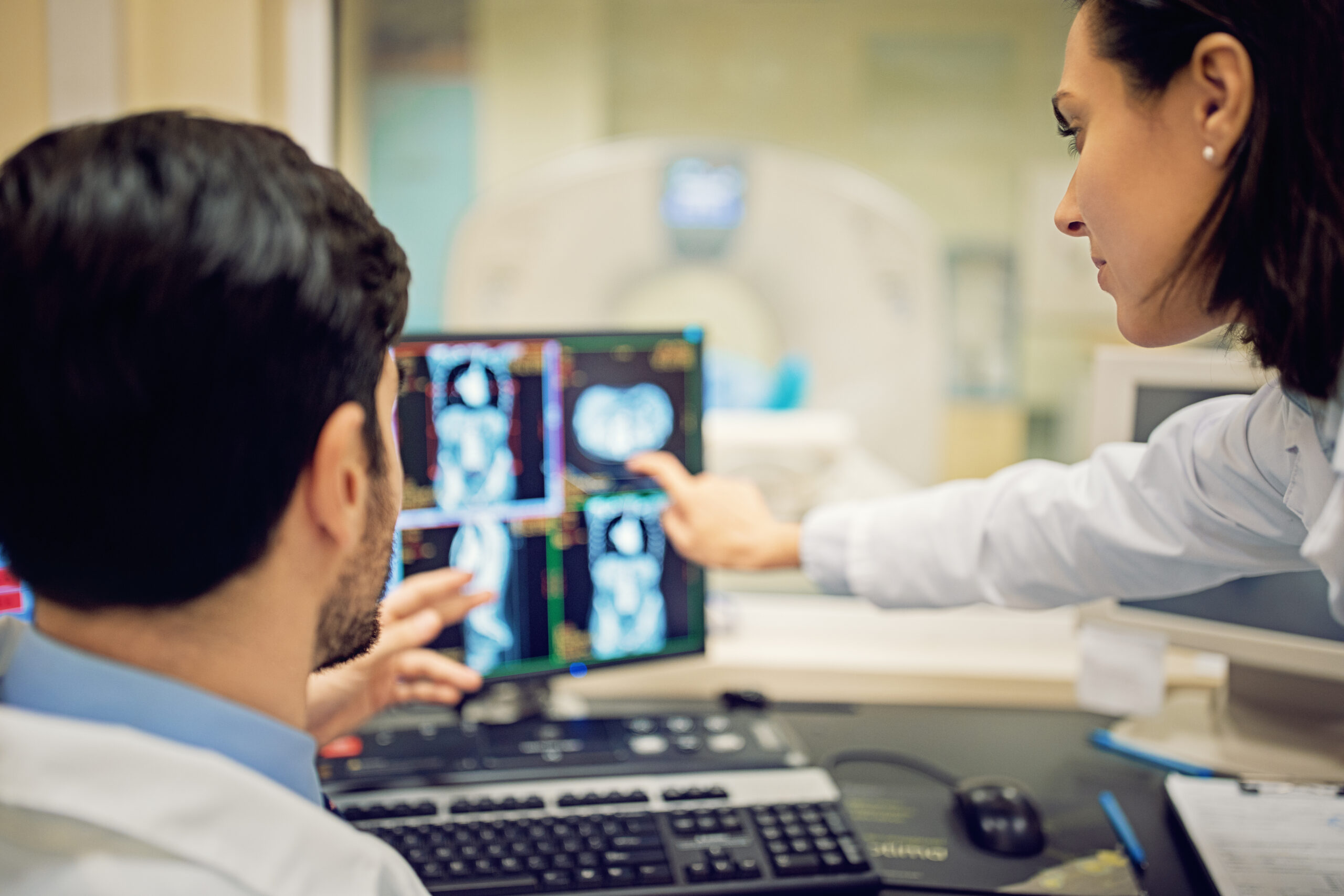 Two doctors observe medical scans on a computer.