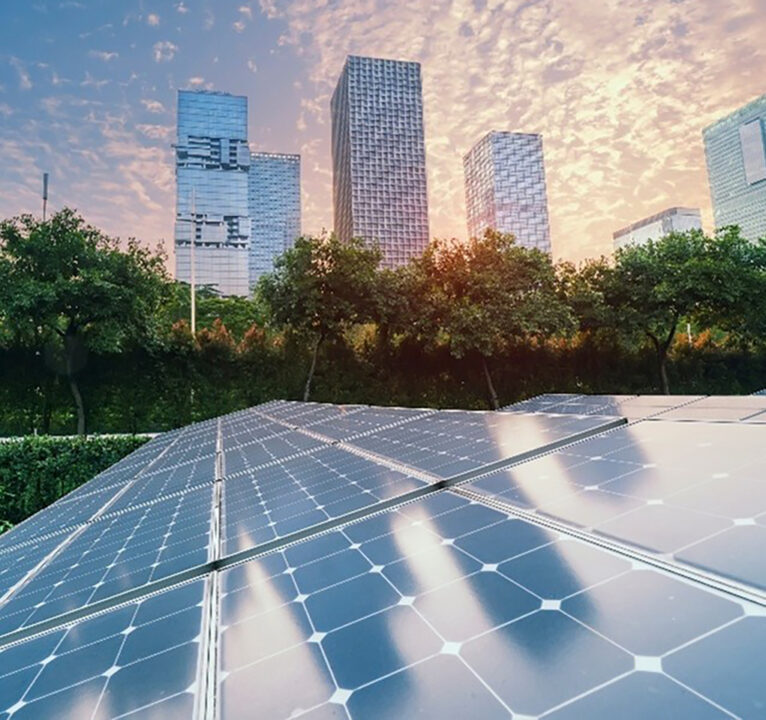 An array of solar panels with office buildings in the background.